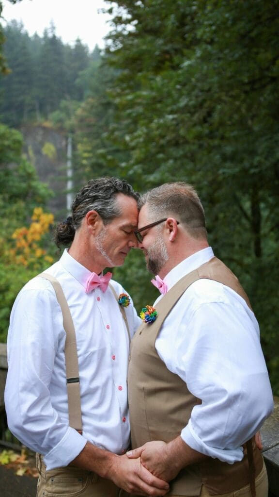 Two grooms sharing an intimate moment in a forest setting during their Oregon elopement