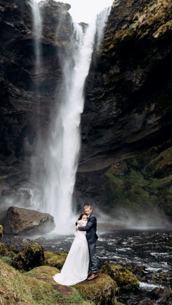 Couple embracing in front of a waterfall during their Oregon elopement ceremony
