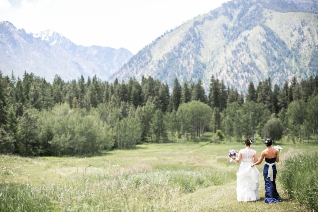 Two brides walking through a meadow with mountain views near Portland, Oregon