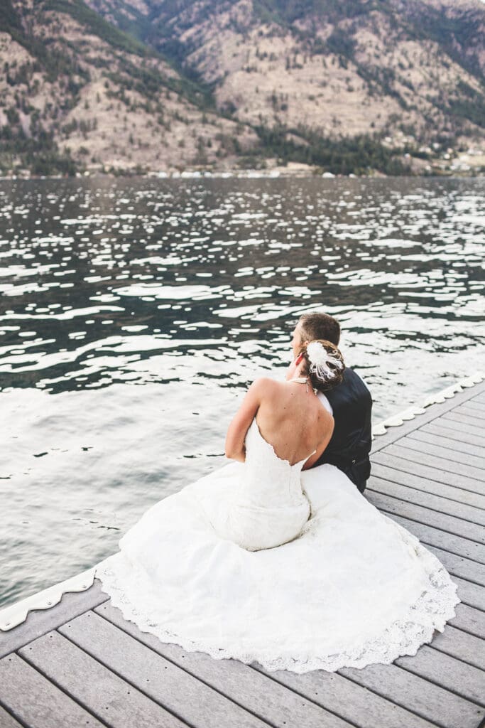 Couple sits along an Oregon Lake right after their wedding ceremony.