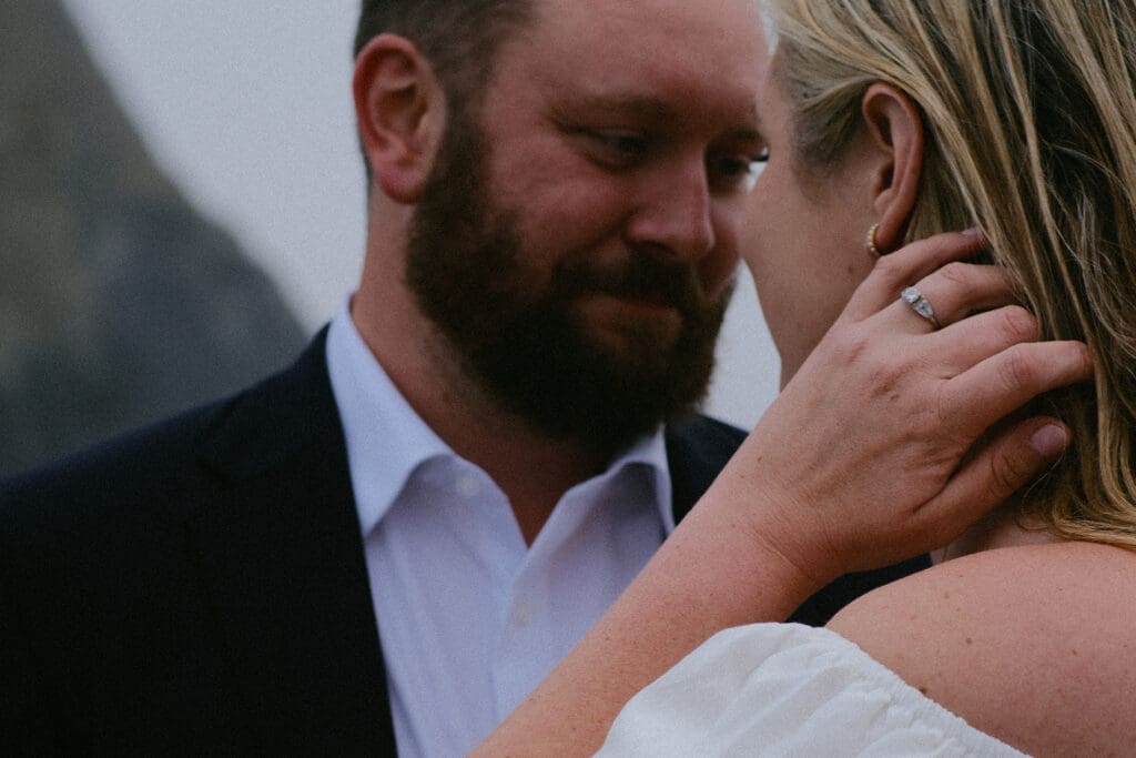 Close up of groom smiling at bride as she touches his face during an elopement in Oregon