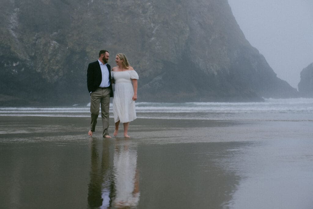 Couple walking hand in hand on the wet sand at their Cannon Beach elopement.


