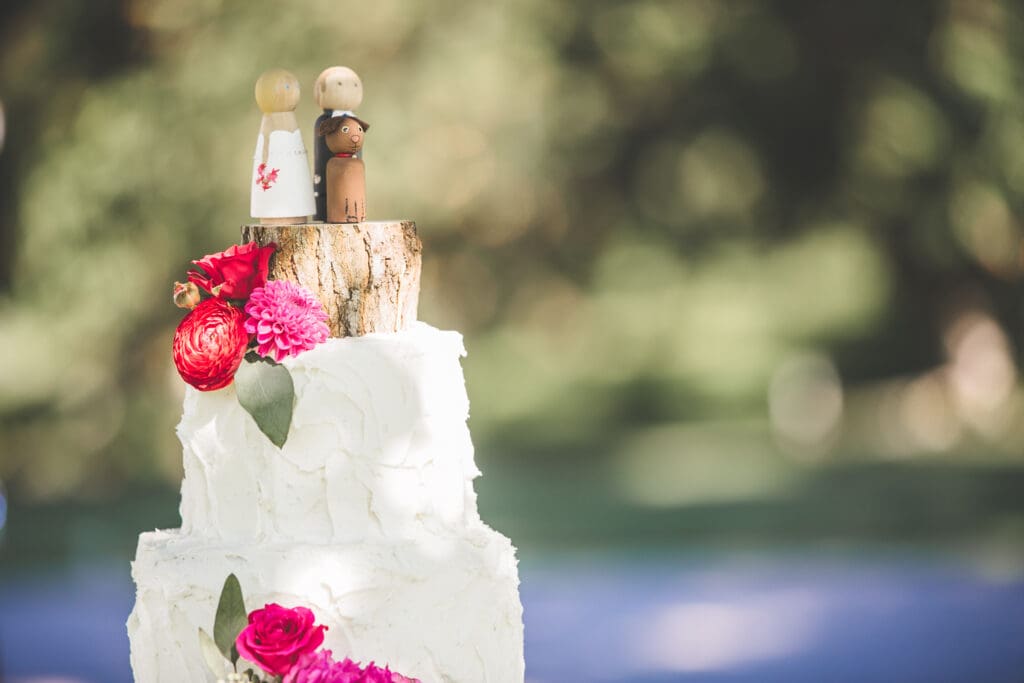 Small white elopement cake with bright flowers and wooden toppers for a budget-friendly PNW elopement


