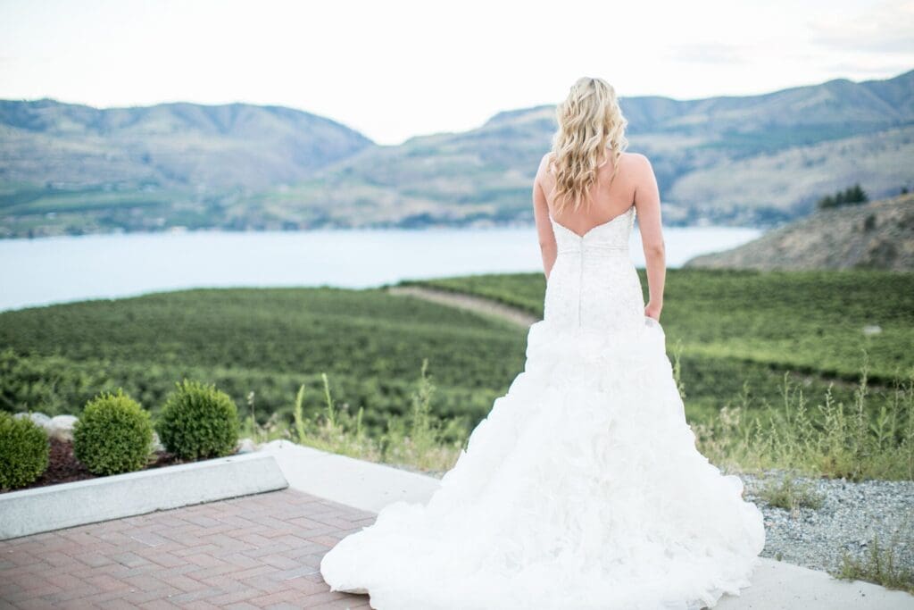 Bride in a white wedding dress overlooking a lake and rolling hills in a Pacific Northwest elopement setting