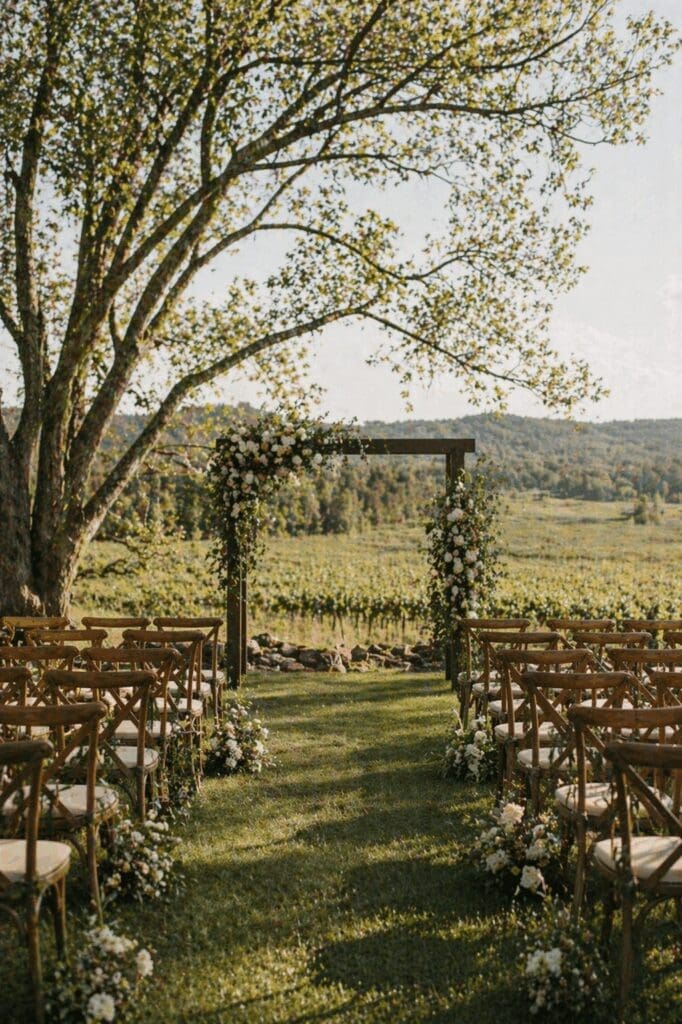 Intimate outdoor wedding ceremony setup with wooden chairs and a simple floral arch overlooking vineyard views in Salem Oregon
