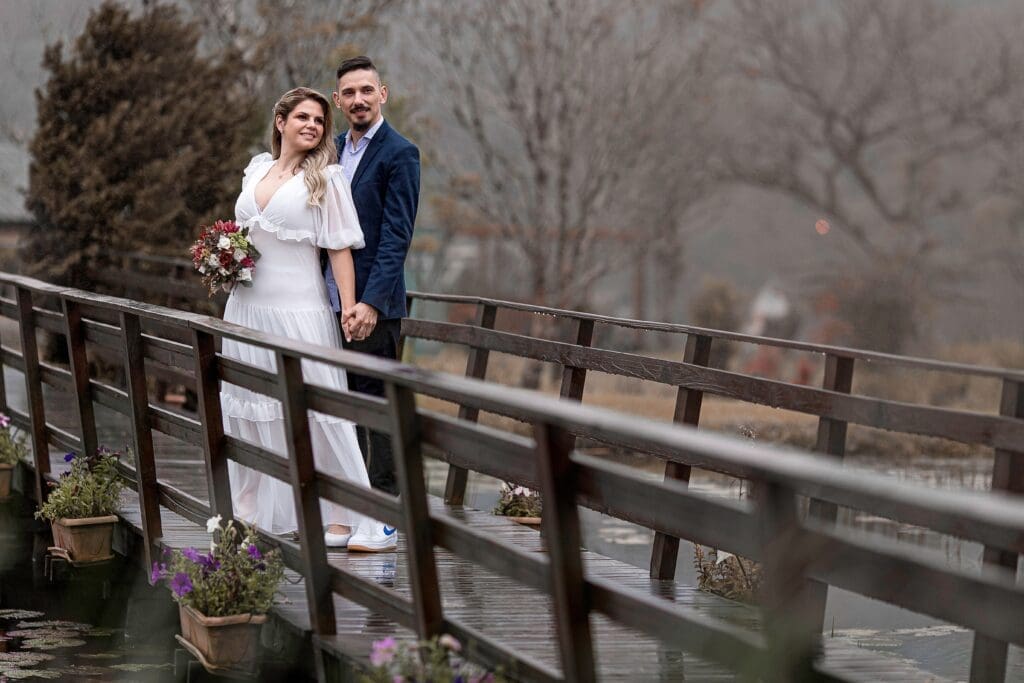 Couple walking across a bridge during light rain, demonstrating how thoughtful elopement backup plans help couples enjoy their wedding day despite changing weather.