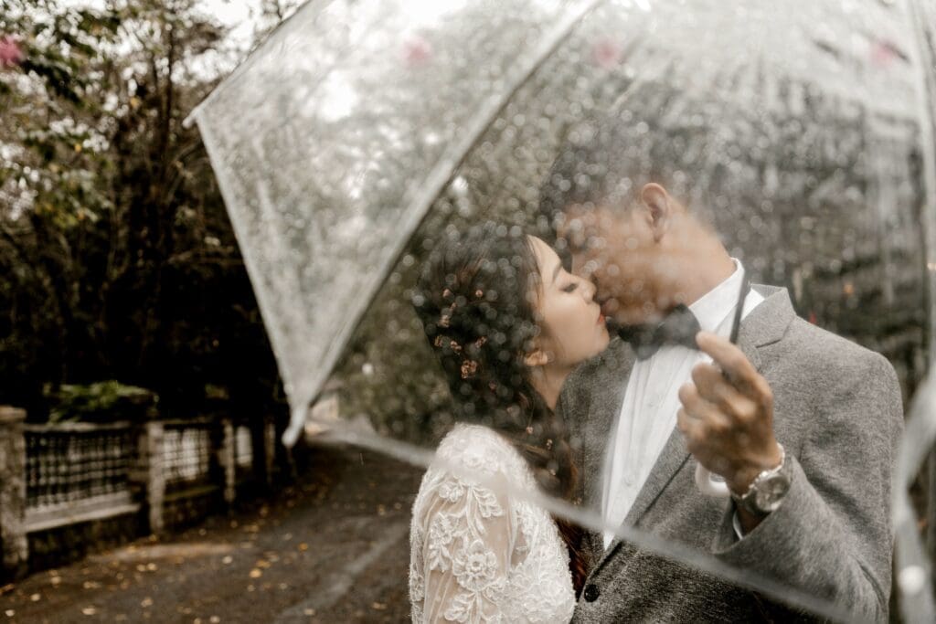 Couple embracing under a clear umbrella during a rainy Pacific Northwest elopement, demonstrating that rain rarely ruins a wedding day.