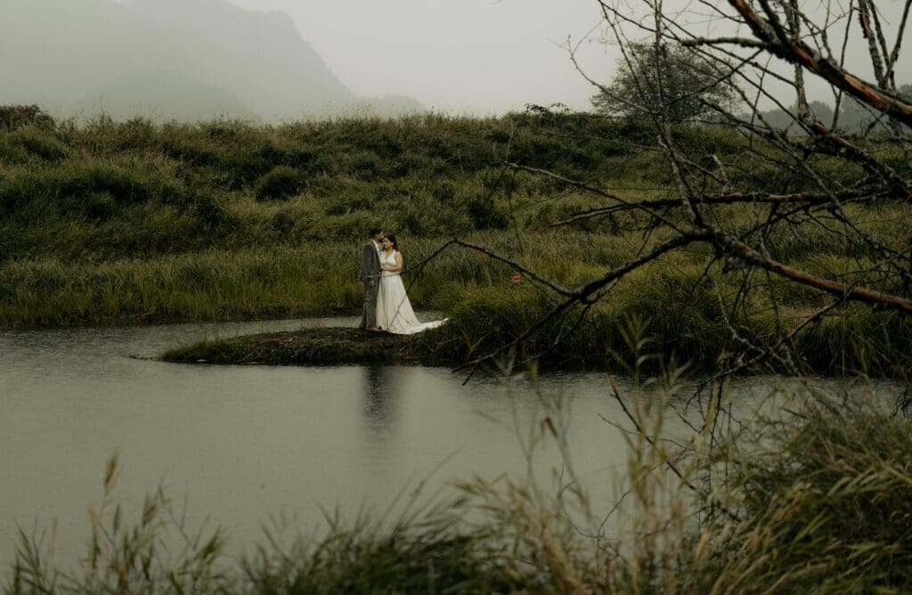 Couple standing beside a lake during a rainy Pacific Northwest elopement, showing how PNW weather can create a beautiful wedding day atmosphere.