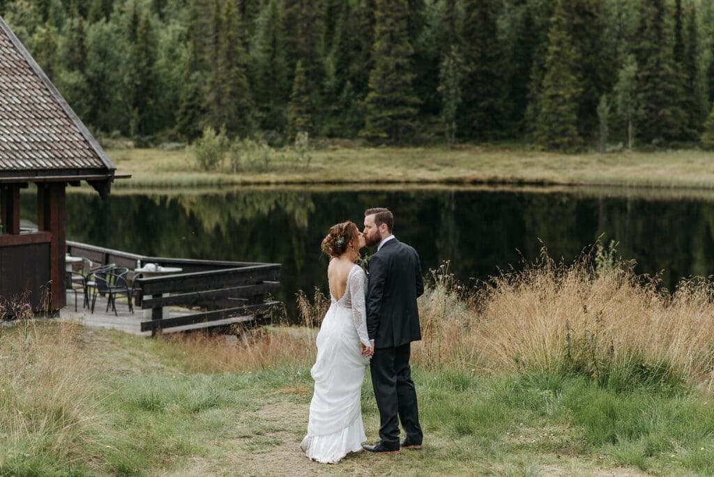 Couple standing beside a forest lake during a Washington elopement with evergreen trees and waterfront views in the background.