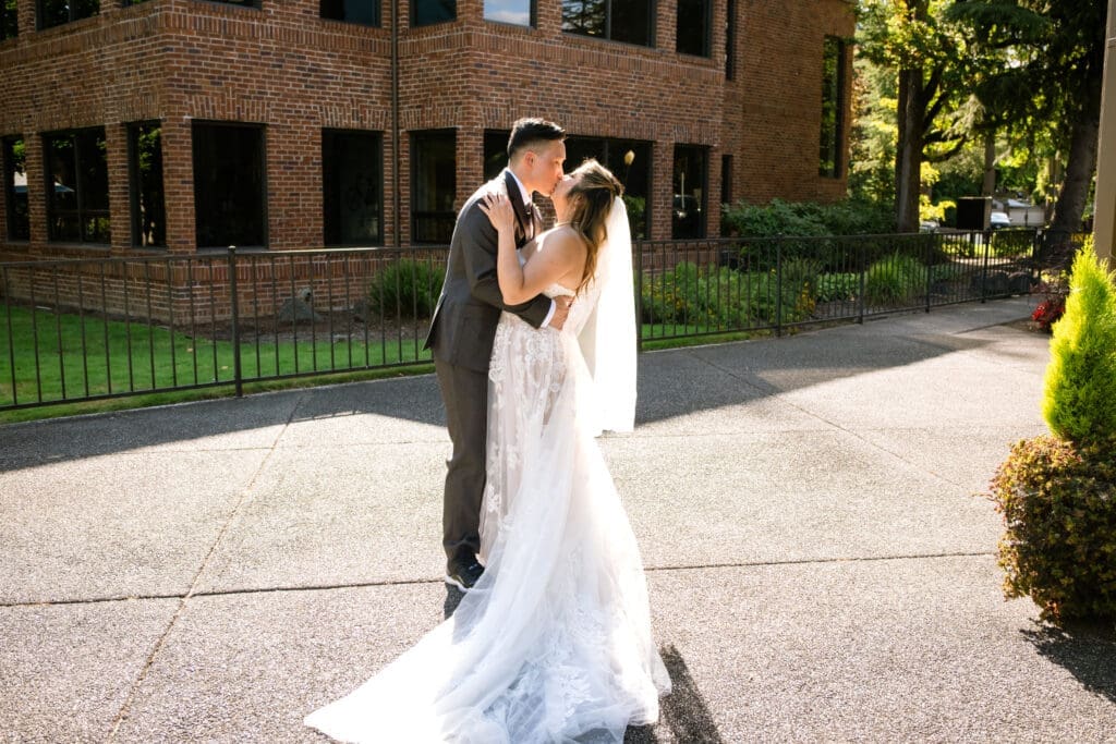 Bride and groom share a kiss outside the brick venue at their Lake Oswego wedding

