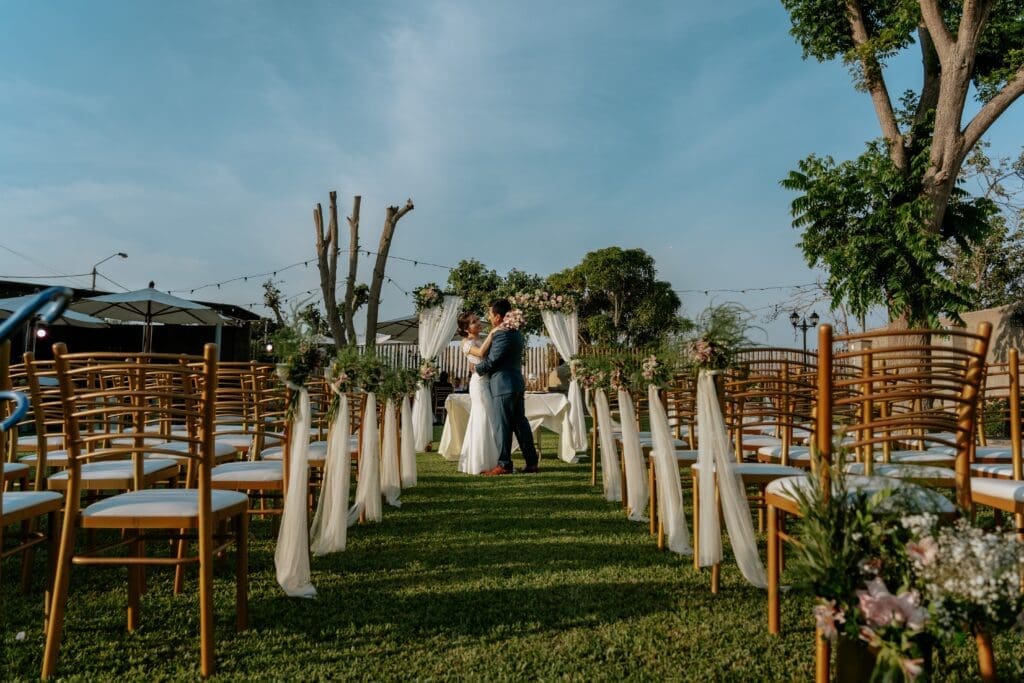 Bride and groom embrace at the altar of a garden ceremony, framed by decorated chairs and florals, illustrating the cohesive design and logistics a full-service Oregon Coast wedding planner can bring to intimate weddings and micro weddings.