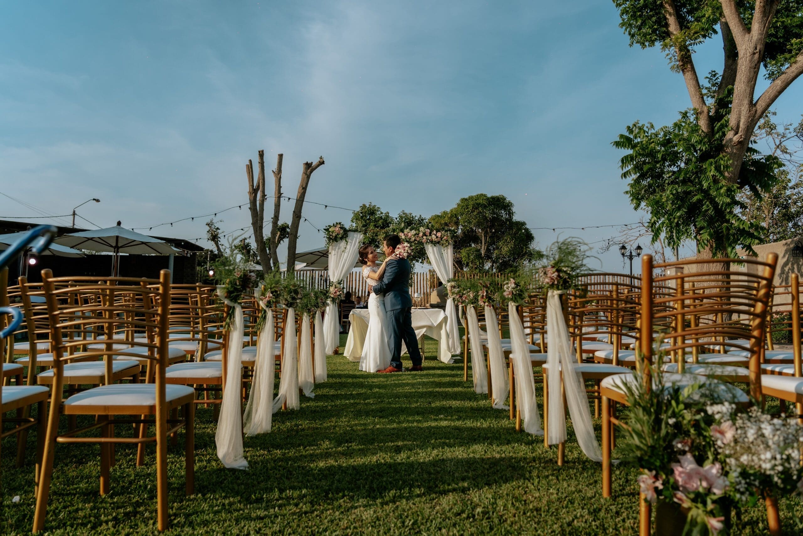 Bride and groom embrace at the altar of a garden ceremony, framed by decorated chairs and florals, illustrating the cohesive design and logistics a full-service Oregon Coast wedding planner can bring to intimate weddings and micro weddings.