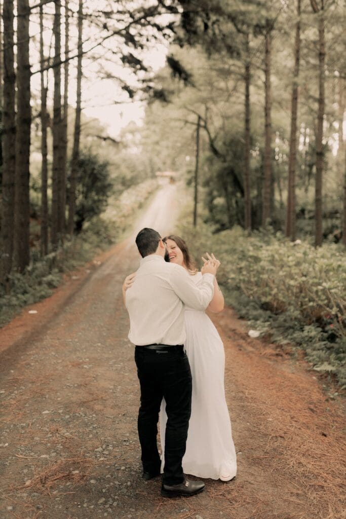 Couple sharing a joyful dance on a tree-lined forest road, enjoying their Oregon Coast wedding while their day-of coordinator manages logistics behind the scenes.