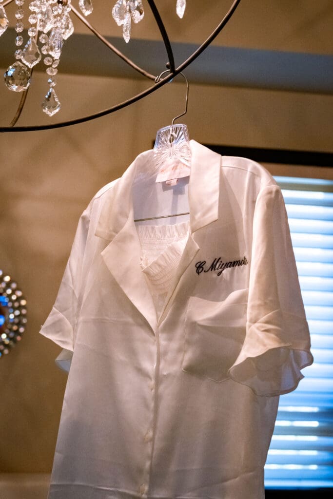 Bride's white getting-ready shirt embroidered with C. Miyamoto hanging before the Lake Oswego wedding