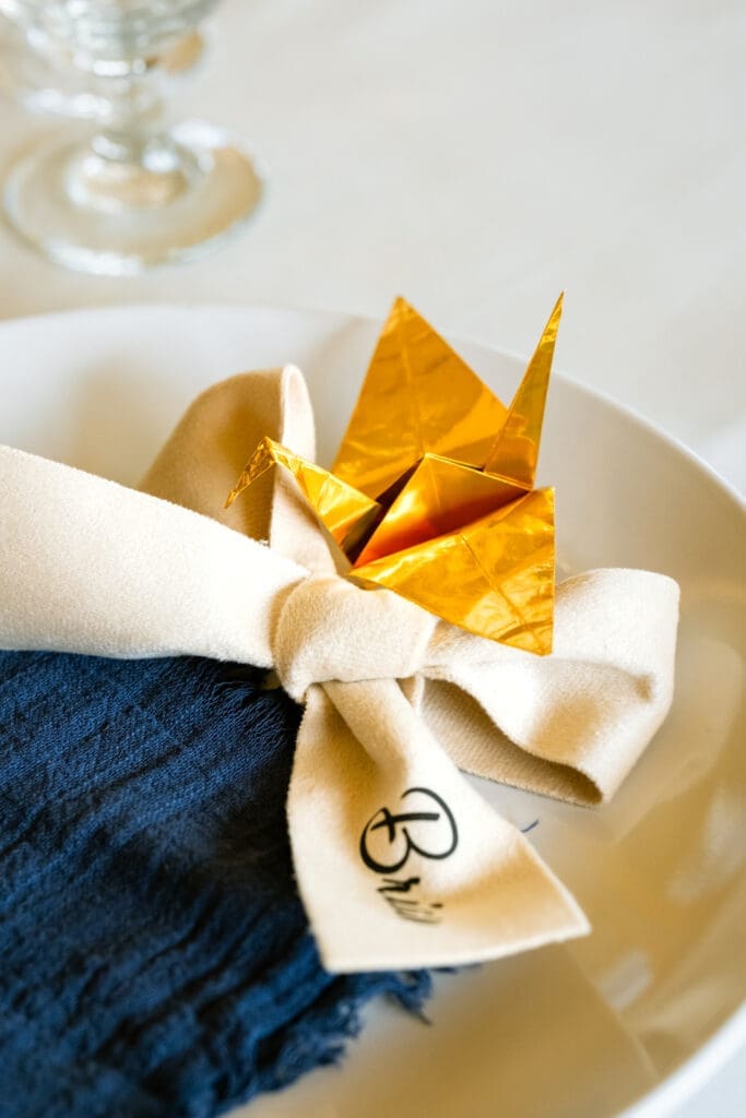 Place setting with a gold origami crane and navy napkin at a Portland intimate wedding reception
