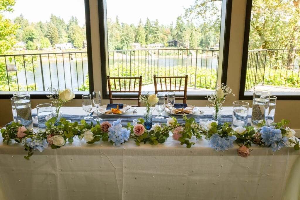 Sweetheart table with a blue and white floral garland overlooking the river at a Portland intimate wedding
