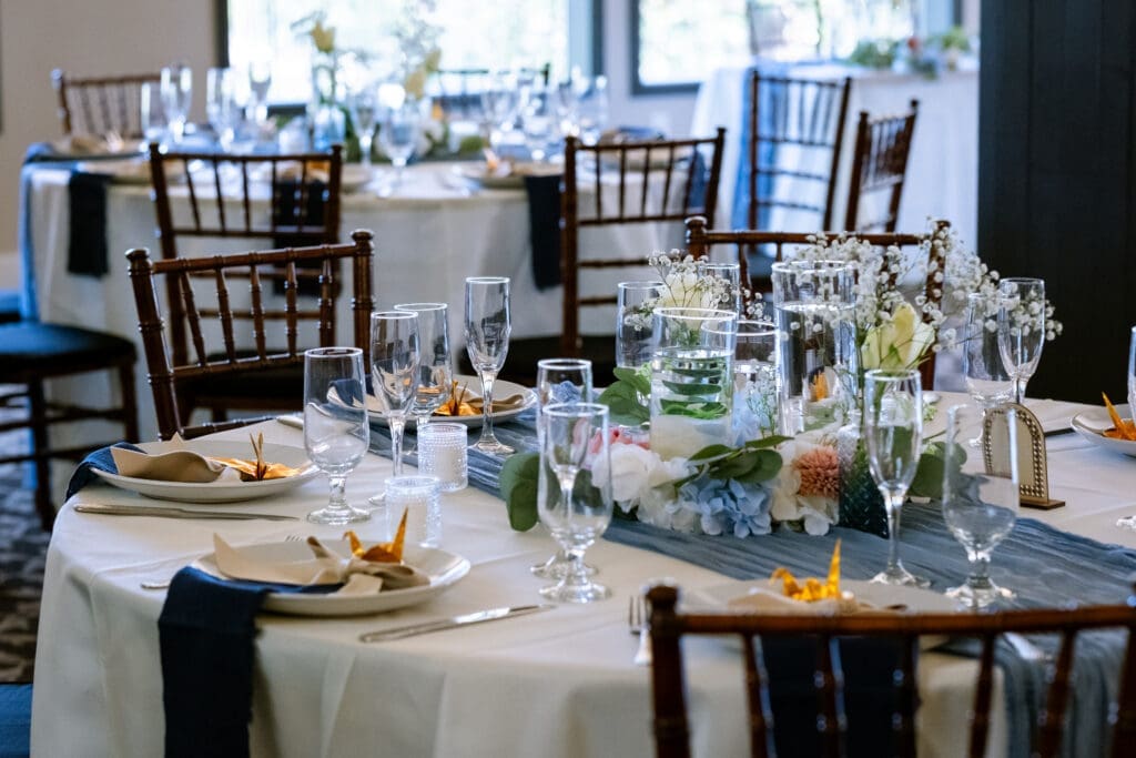 Reception tables set with blue and white florals and glassware at a Lake Oswego wedding