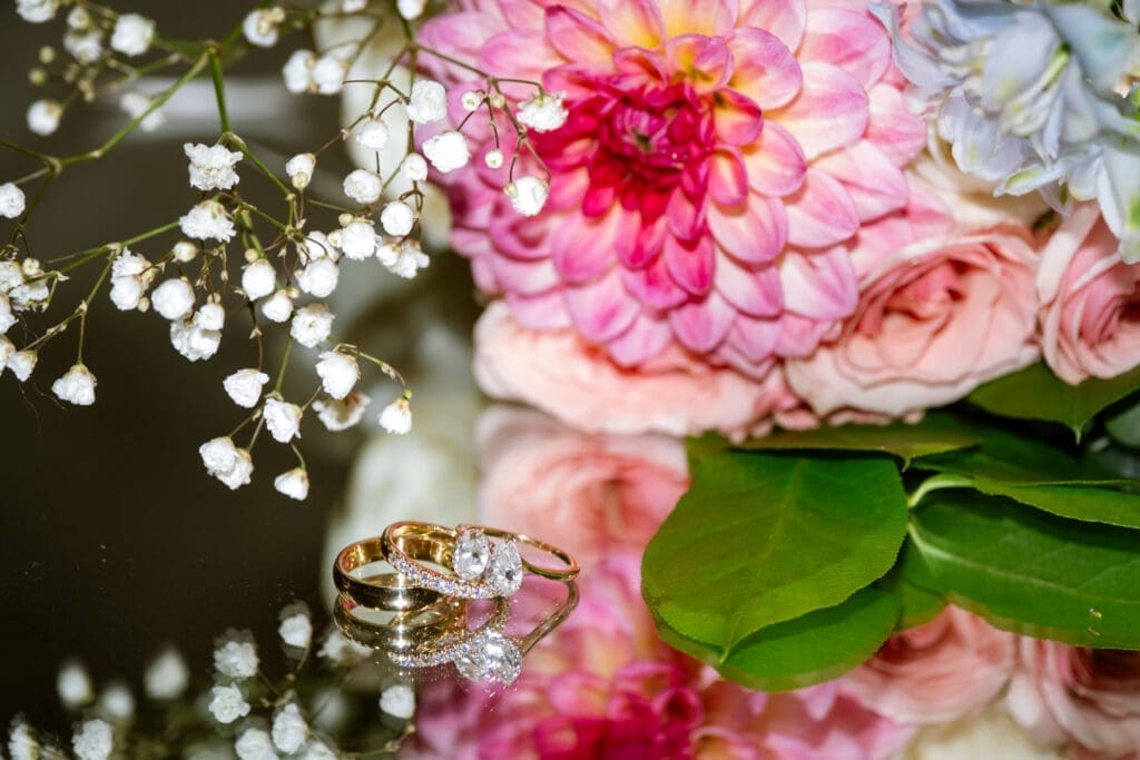 Wedding rings resting beside the bride's pink bouquet and baby's breath at their Lake Oswego wedding