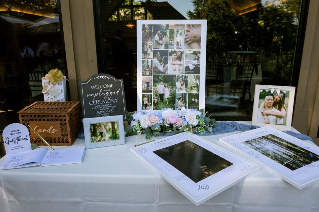 Reception welcome table with a photo collage, guest book, and card box at The Foundry in Lake Oswego