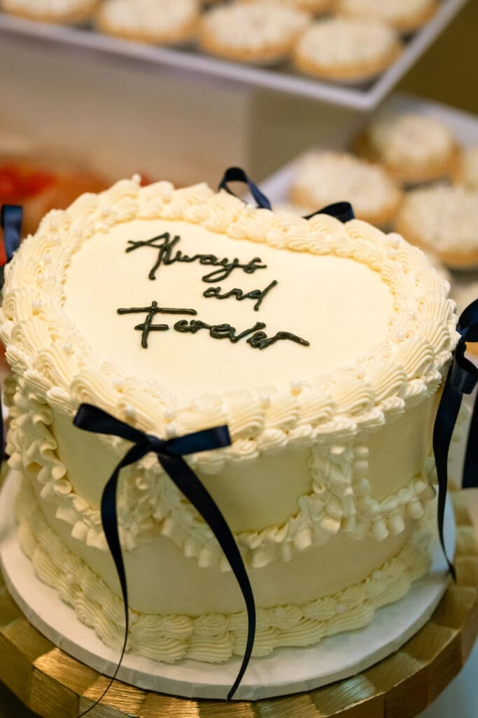 White heart-shaped wedding cake reading Always and Forever with navy bows at a Lake Oswego wedding