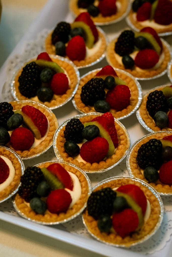 Tray of fresh fruit tarts topped with berries and kiwi at a Lake Oswego wedding dessert table
