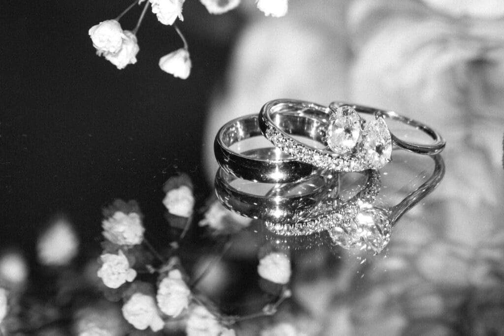 Close-up of the wedding rings resting on a mirror with baby's breath at Carla and Eric's wedding