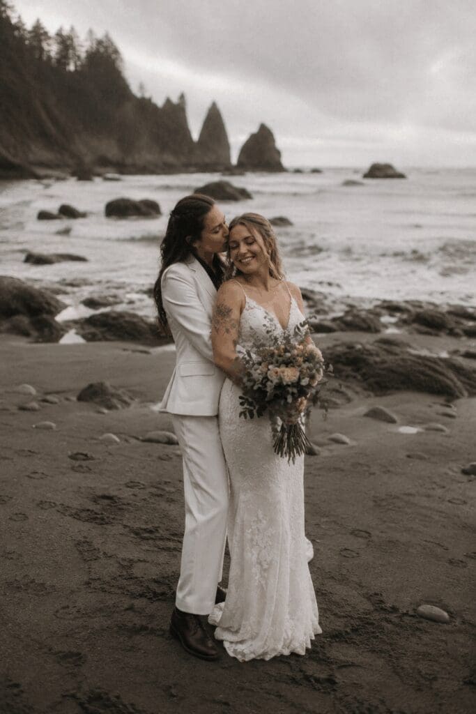 Couple in wedding attire embracing on a rocky Oregon Coast beach