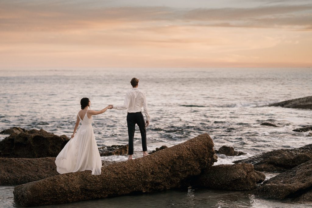 Couple holding hands on coastal rocks during a Brookings Oregon wedding at sunset